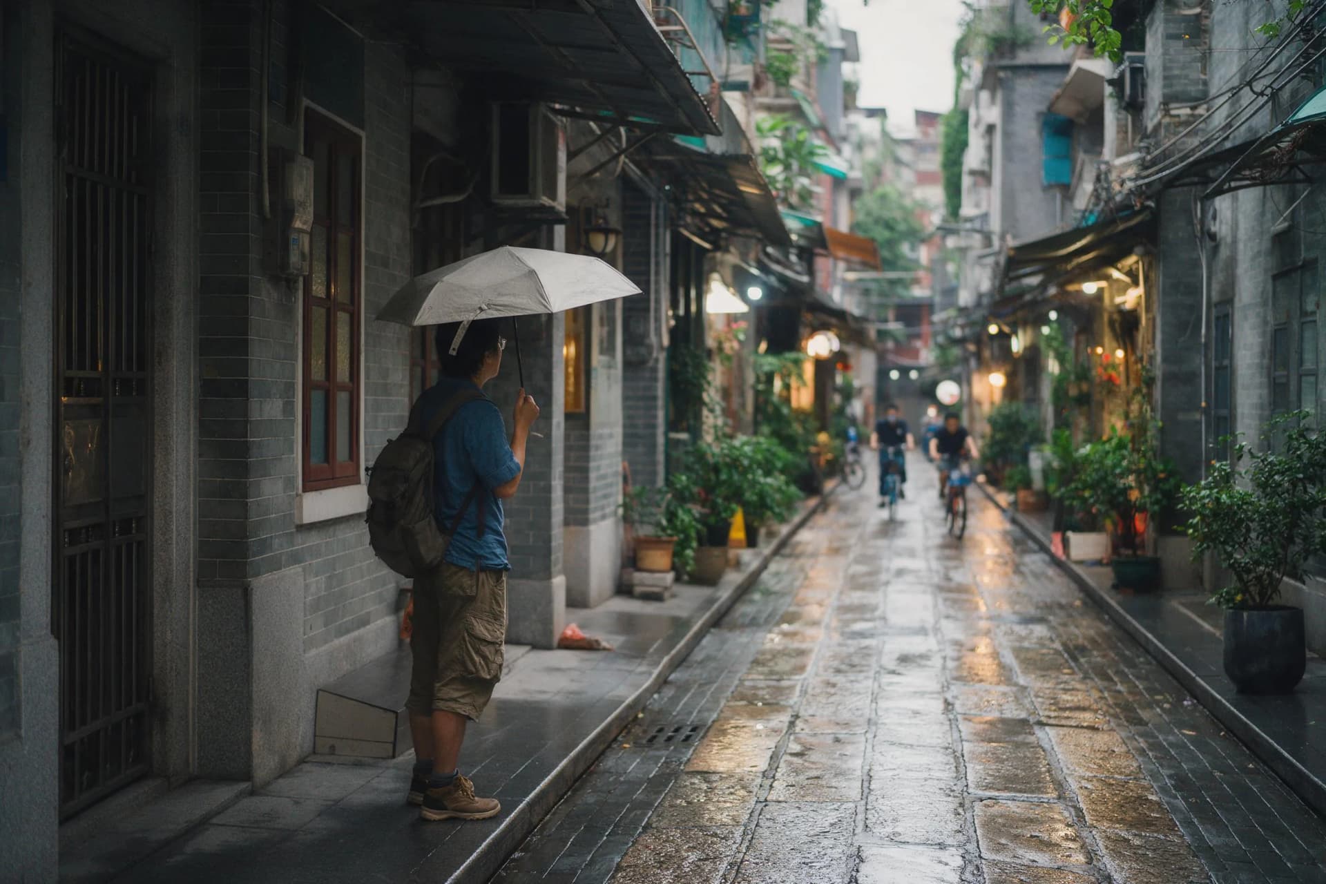 Rainy morning in a Guangzhou neighborhood arcade with wet stone lanes and traveler under umbrella