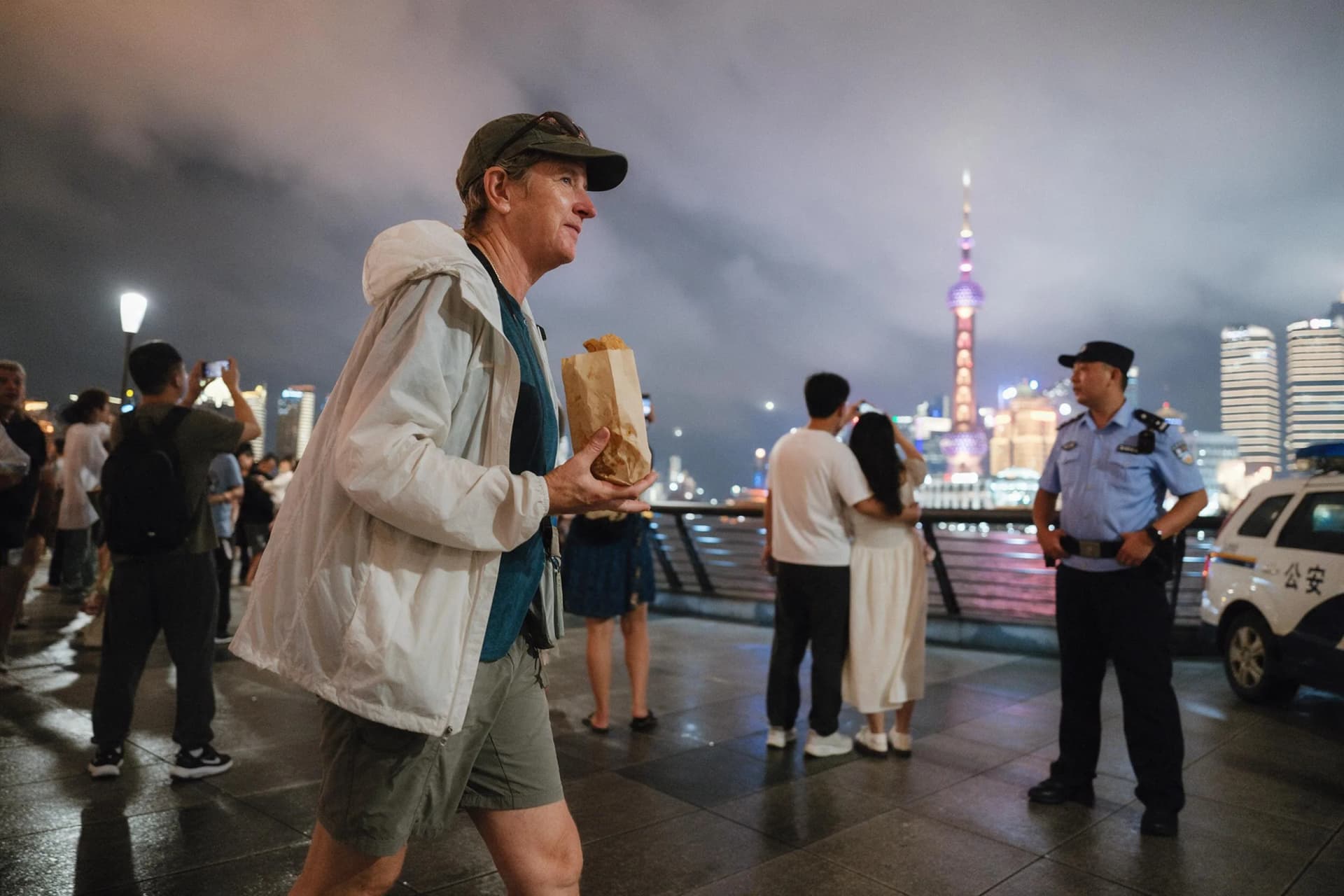 American tourist walking a lit Shanghai riverside promenade at night, China safety guide 2026