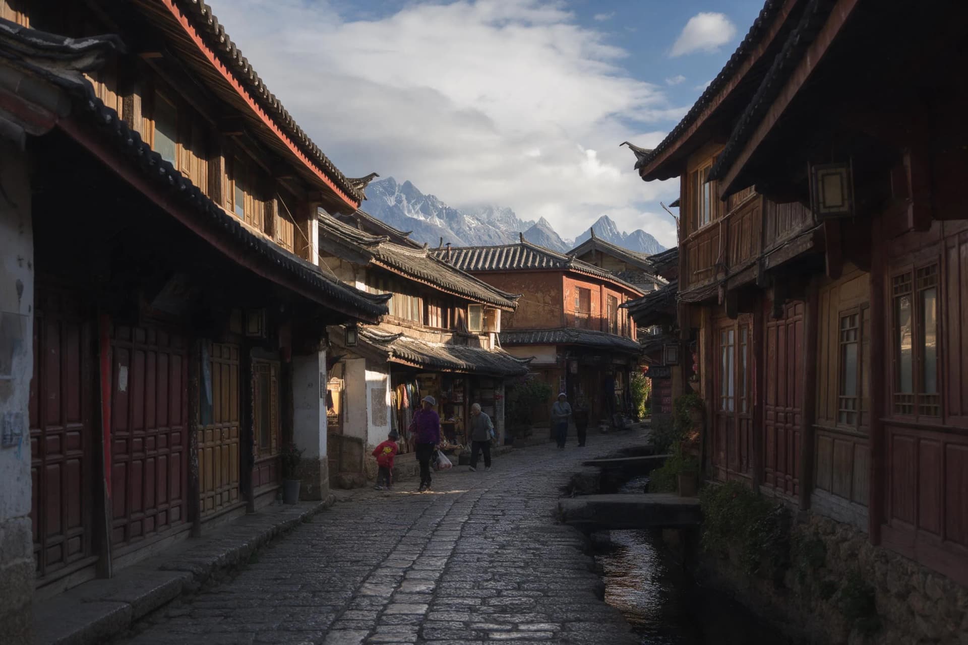 Early morning stone lane and timber roofs in Lijiang Old Town with Jade Dragon Snow Mountain beyond