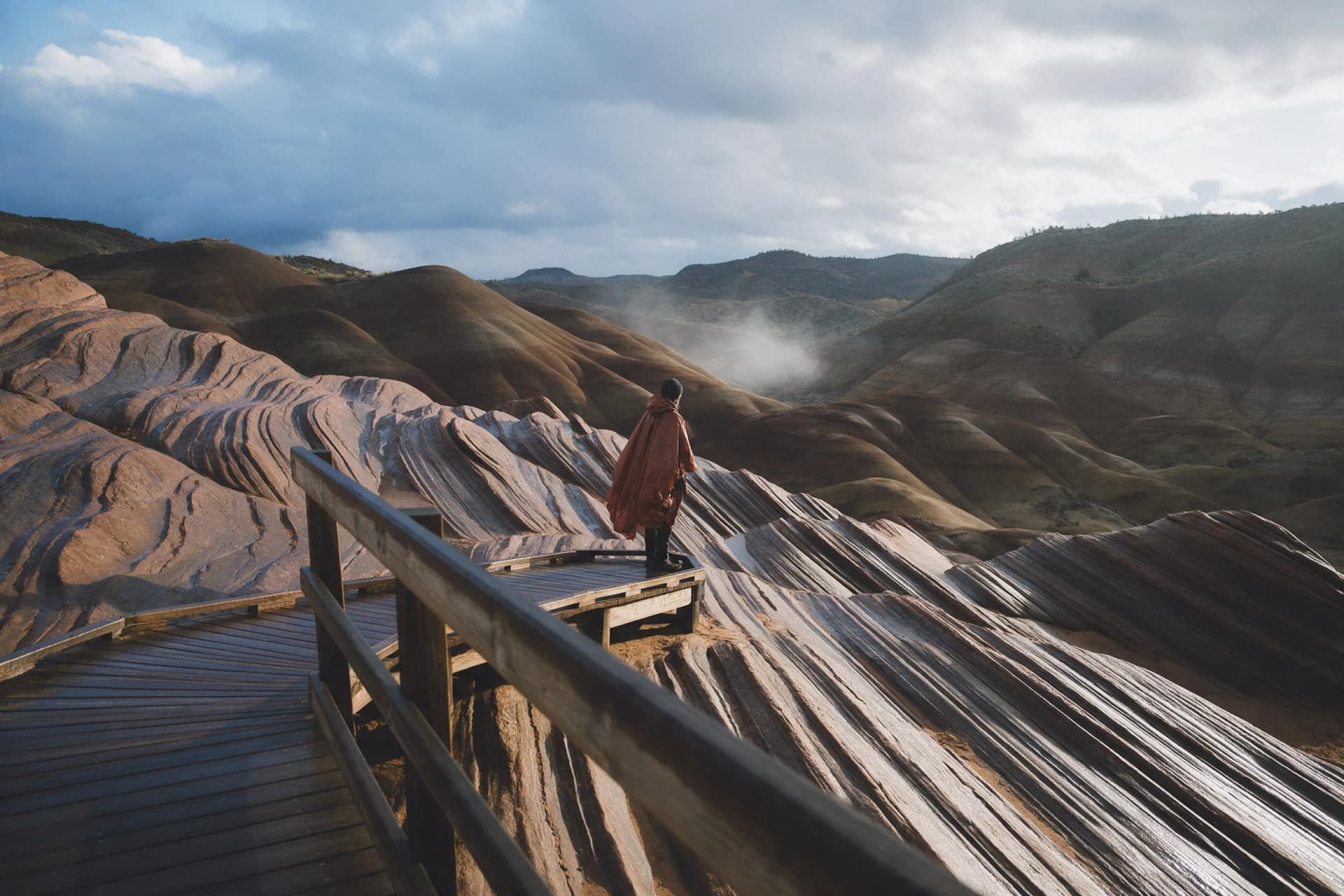 Travel photographer's view of Rainbow Mountains in Zhangye at misty first light from a wooden walkway