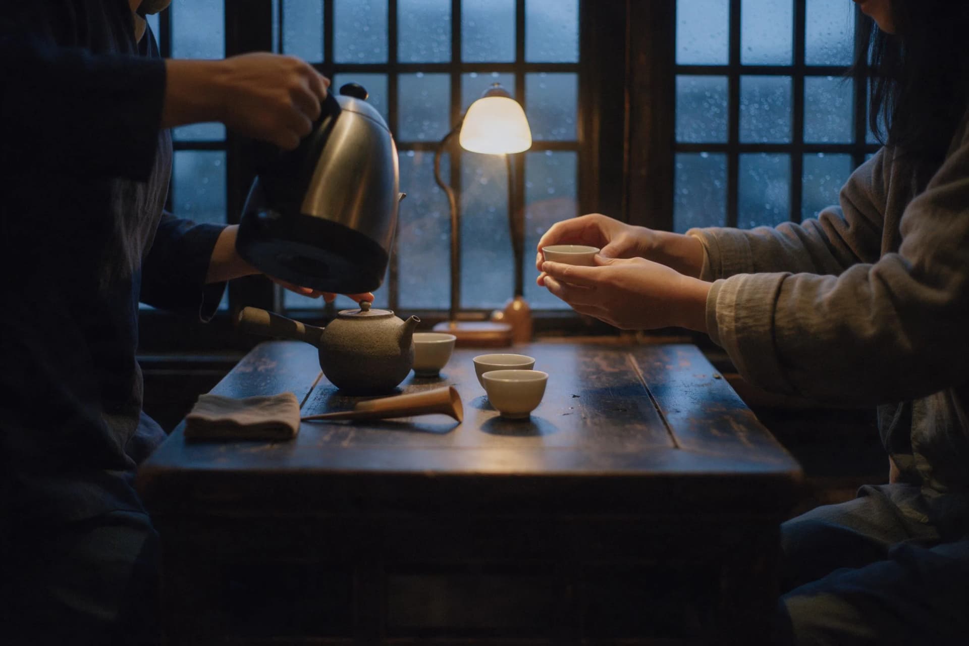 A 35mm travel photo of a Chinese tea-house server pouring tea into small porcelain cups on a wooden table at blue hour